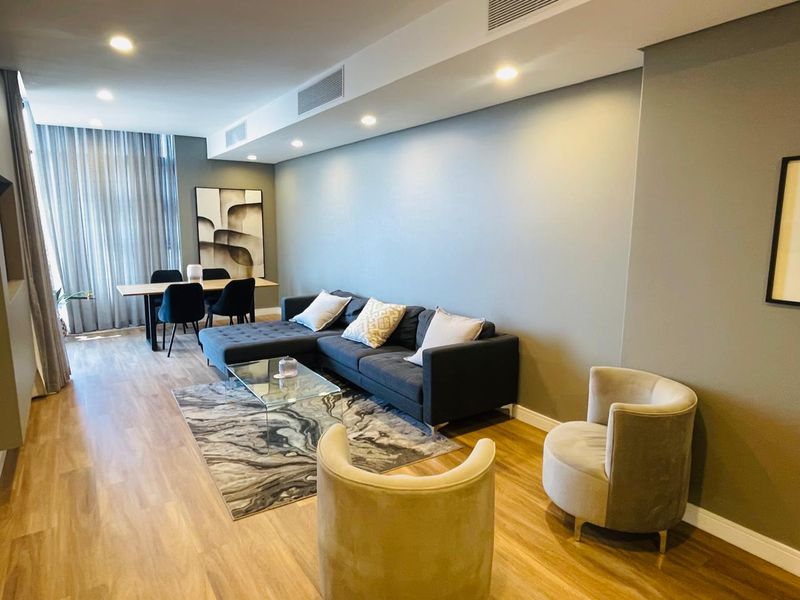 A modern open-plan living and dining area featuring laminate flooring, recessed downlighting, and integrated ducted air conditioning.