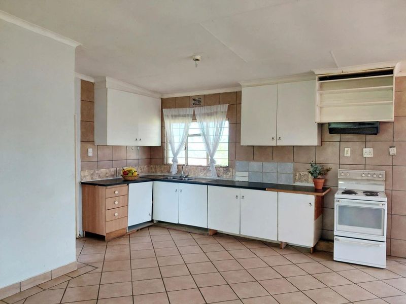 A functional kitchen featuring tiled flooring, a tiled backsplash, built-in cabinetry, and a freestanding stove, offering potential for modernization.
