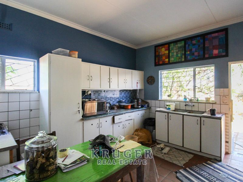 A functional kitchen featuring built-in cabinetry, a double sink, and a tiled backsplash, offering potential for modernization and aesthetic updates.