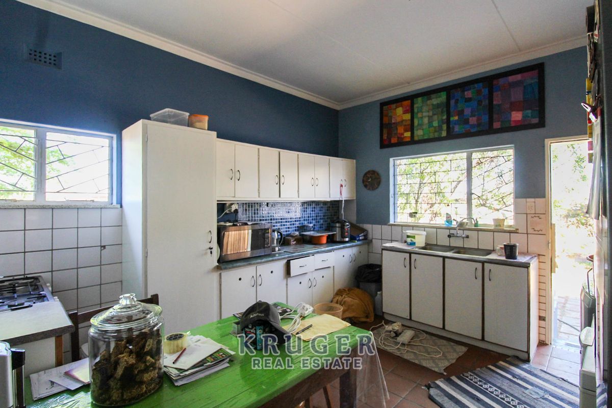 A functional kitchen featuring built-in cabinetry, a double sink, and a tiled backsplash, offering potential for modernization and aesthetic updates.