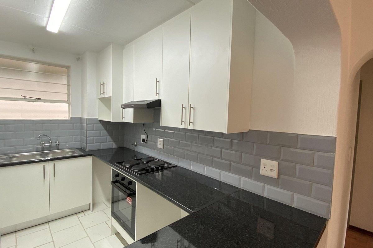 A clean, modern kitchen featuring white cabinetry, black granite countertops, subway tile backsplash, and integrated stainless steel appliances.
