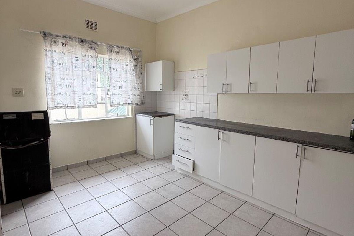 A functional kitchen featuring white cabinetry, tiled flooring, and a tiled backsplash, offering a clean canvas for potential modern updates.