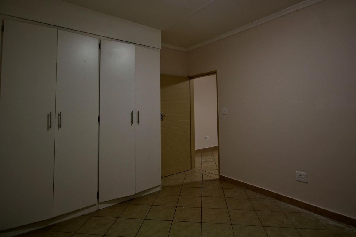 An empty bedroom featuring built-in cupboards and tiled flooring, offering a neutral space ready for personalization.