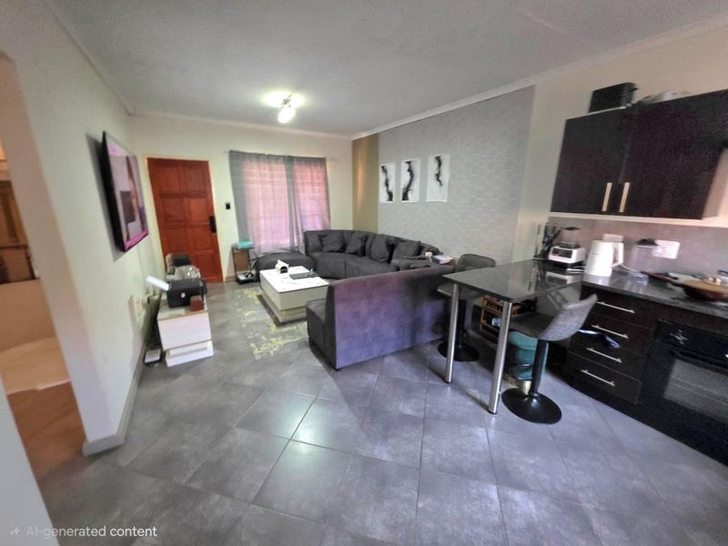 Open-plan living area featuring a compact kitchen with dark cabinetry, stone countertops, and tiled flooring, seamlessly integrated with the lounge space.
