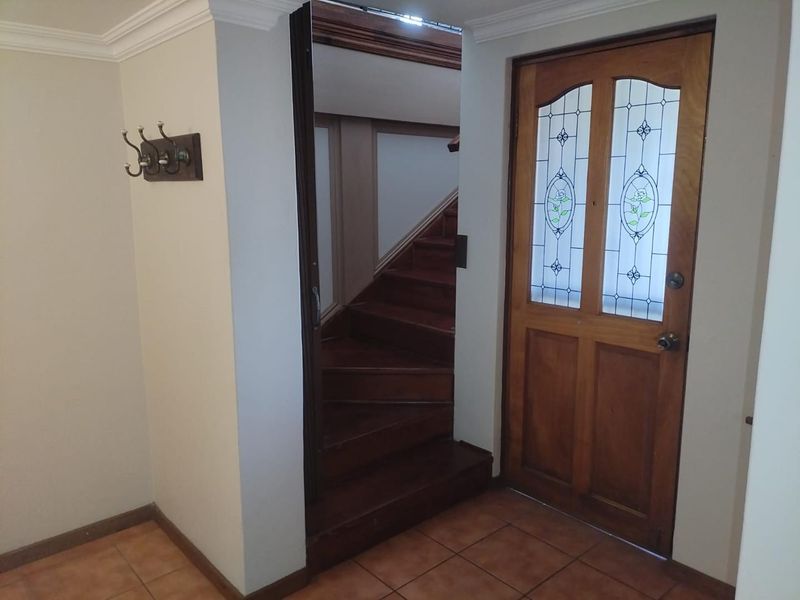 Entrance foyer featuring tiled flooring, a classic timber staircase, and a decorative leaded glass timber front door.