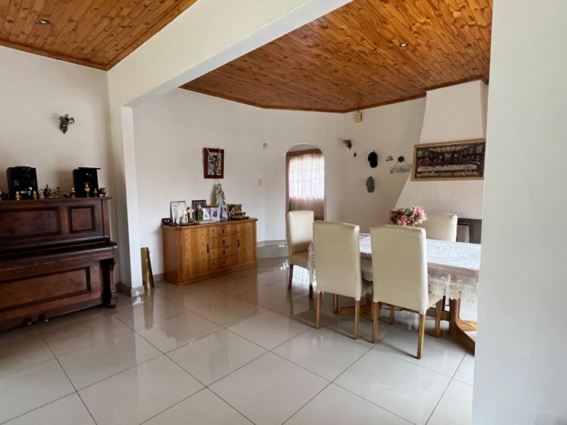Open plan living and dining area featuring polished floor tiles and a distinctive timber tongue and groove ceiling with a built-in fireplace.