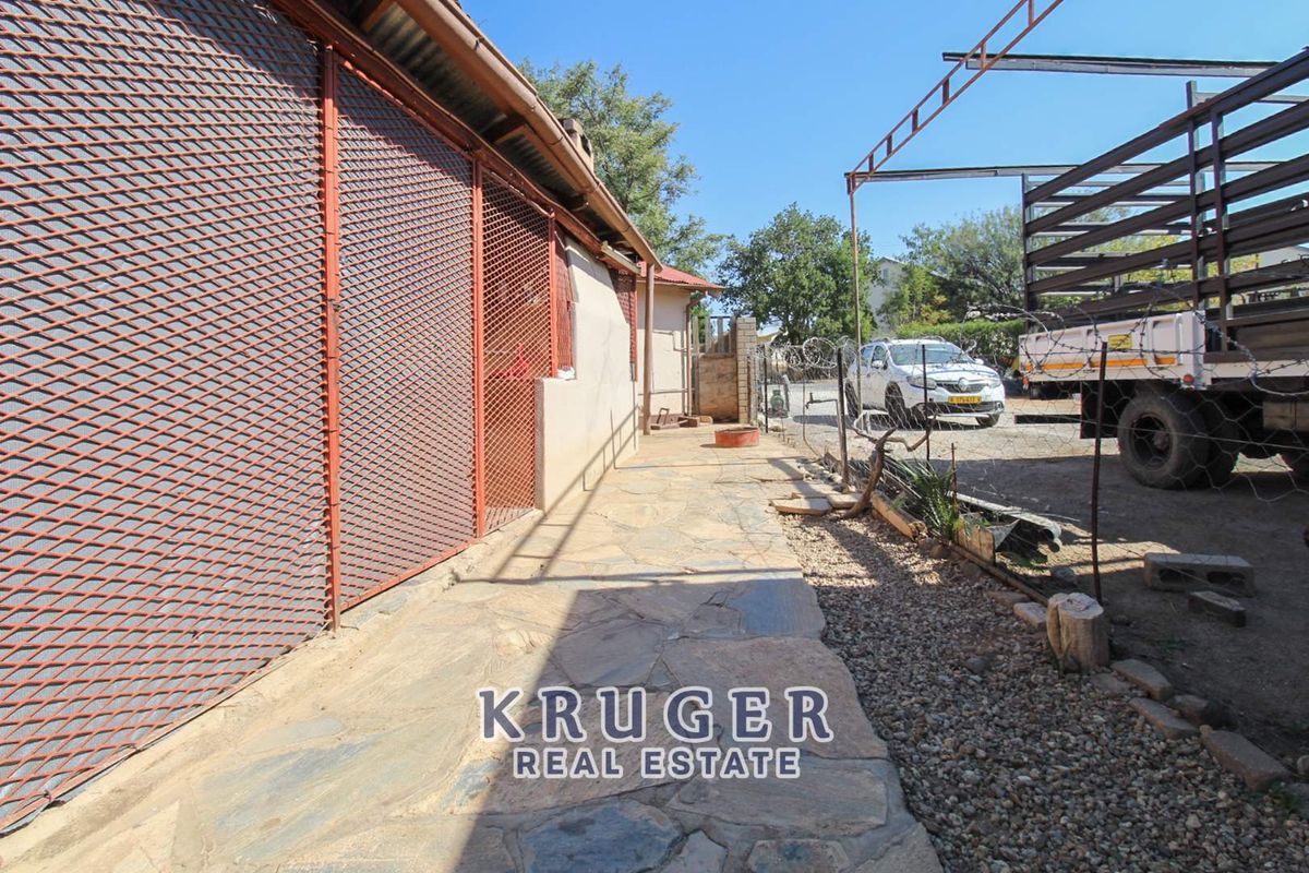 Exterior side walkway featuring stone paving and extensive metal security screening along the building facade.