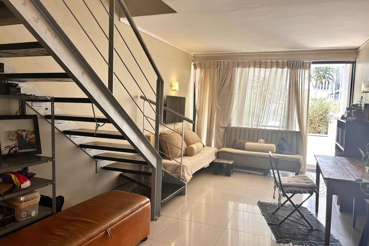 Open-plan living area featuring a modern metal staircase, tiled flooring, and large sliding glass doors providing access to the outdoor space.