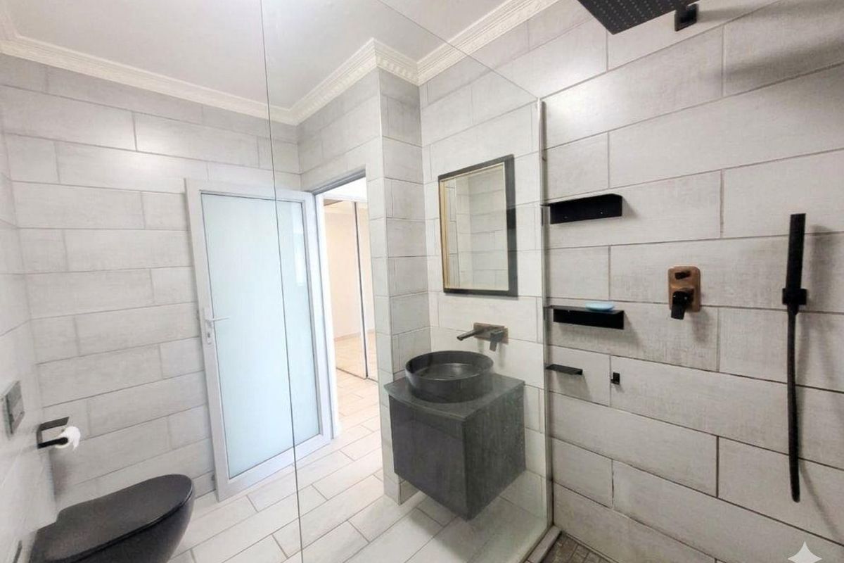 Modern bathroom featuring a walk-in shower with a rain shower head, wall-mounted vanity with a vessel sink, and a wall-hung toilet.