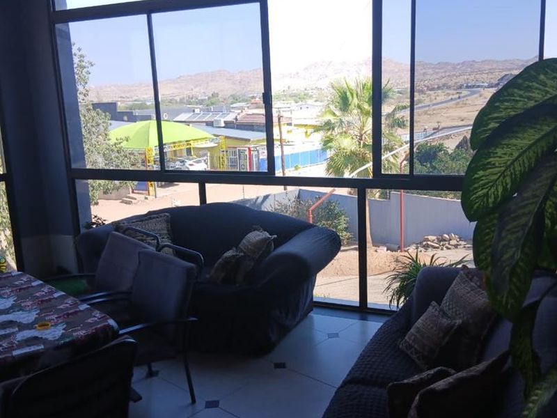 Enclosed patio area featuring a timber ceiling, tiled flooring, and large aluminium sliding windows offering expansive views of the surrounding landscape.