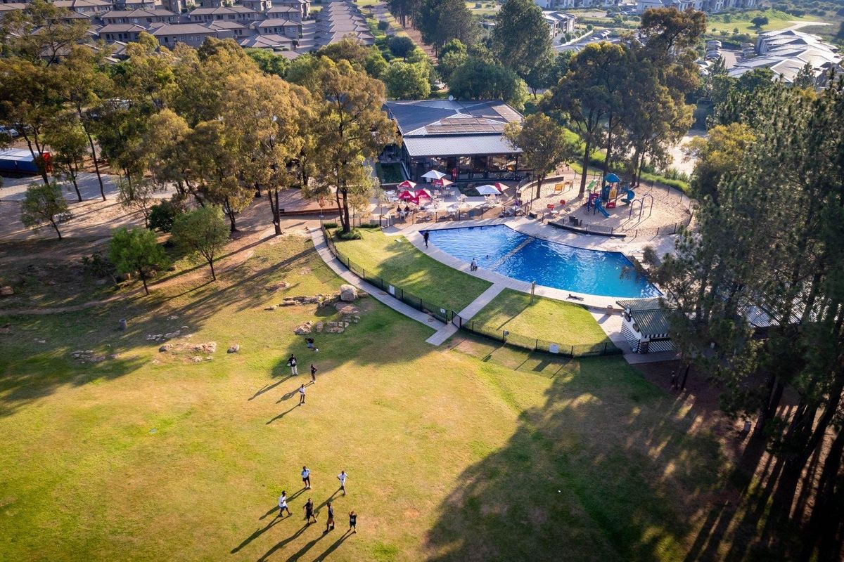 Aerial view of the estate communal facilities, featuring a swimming pool, playground, and clubhouse set within landscaped grounds.