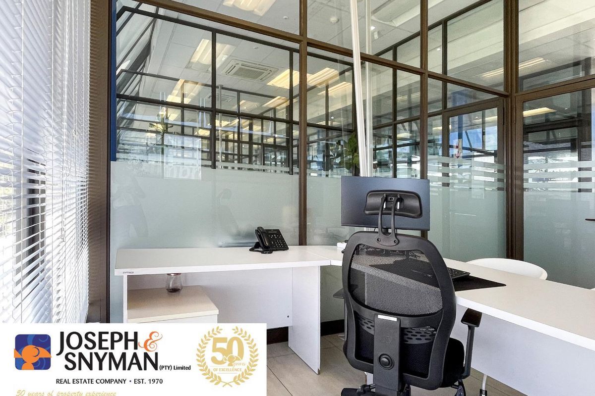 A professional office space featuring glass partitioning, tiled flooring, and recessed ceiling lighting, providing a bright and modern work environment.