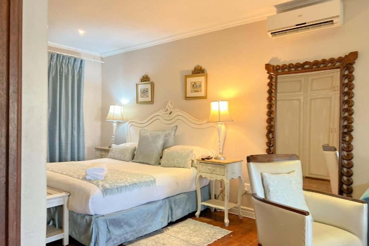 A well-maintained bedroom featuring hardwood flooring, recessed lighting, a wall-mounted air conditioning unit, and built-in closet space with a decorative mirror frame.
