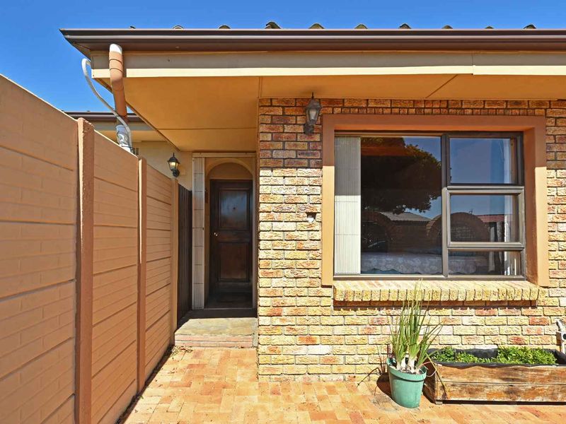 A private rear patio area featuring face brick construction, paved flooring, and a secure precast boundary wall, providing a functional outdoor space.