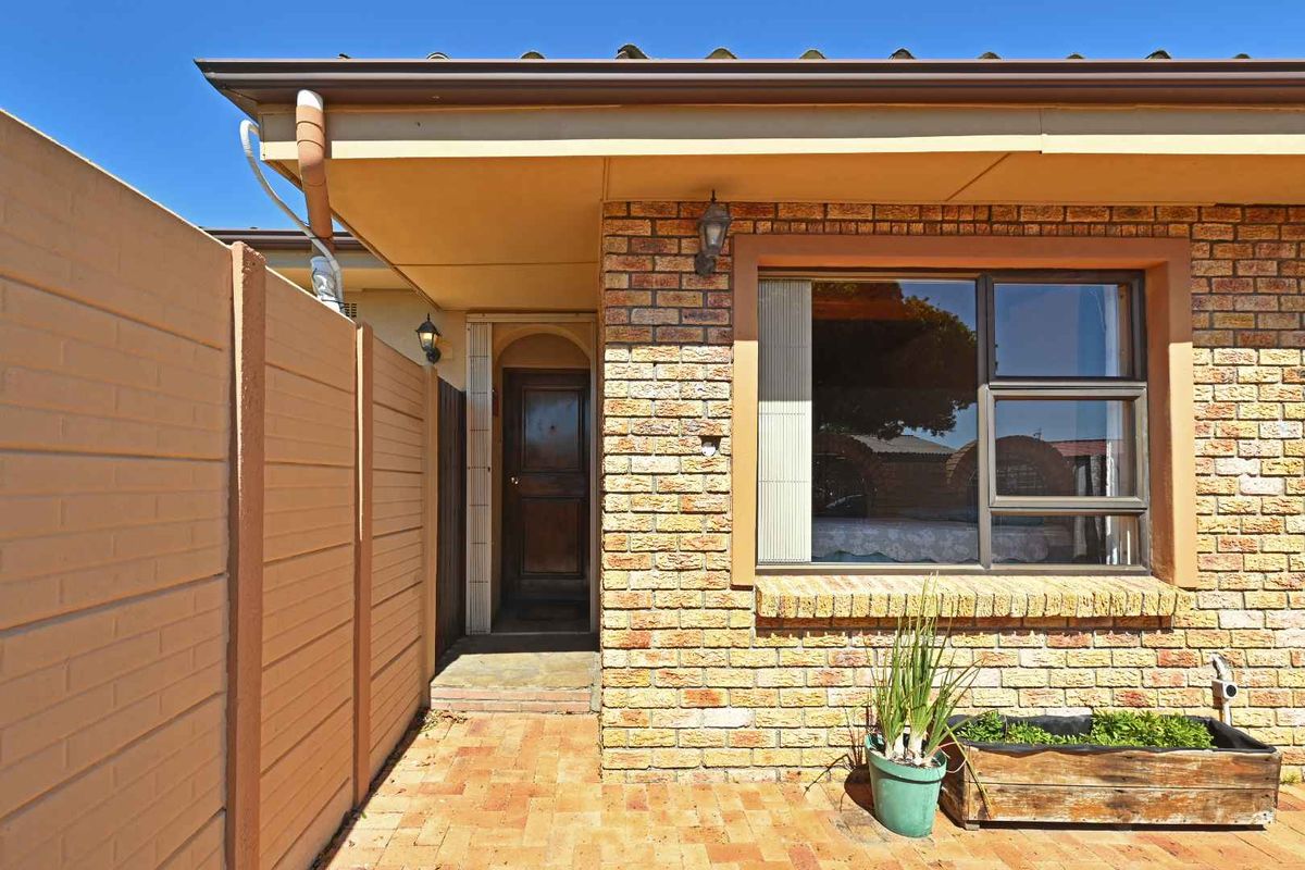 A private rear patio area featuring face brick construction, paved flooring, and a secure precast boundary wall, providing a functional outdoor space.