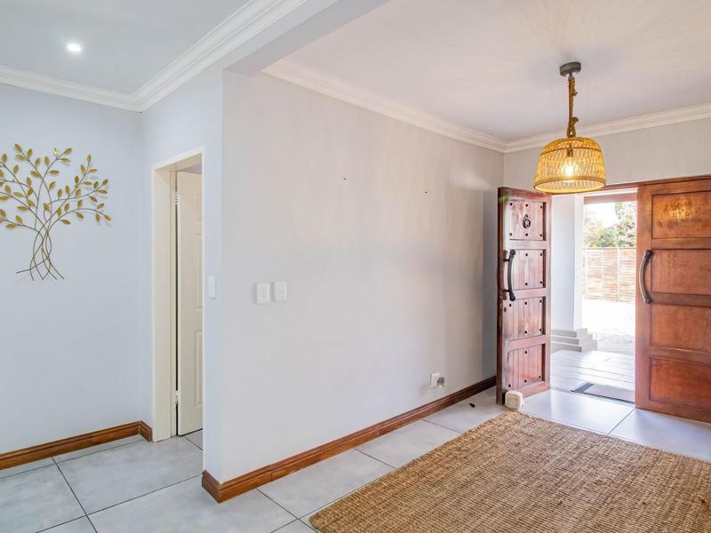 A bright and welcoming entrance hall featuring tiled flooring, decorative cornice, and solid timber double front doors.