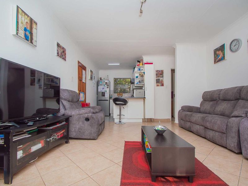 Open-plan living area featuring tiled flooring and a compact kitchen with a breakfast counter, creating a functional and connected living space.