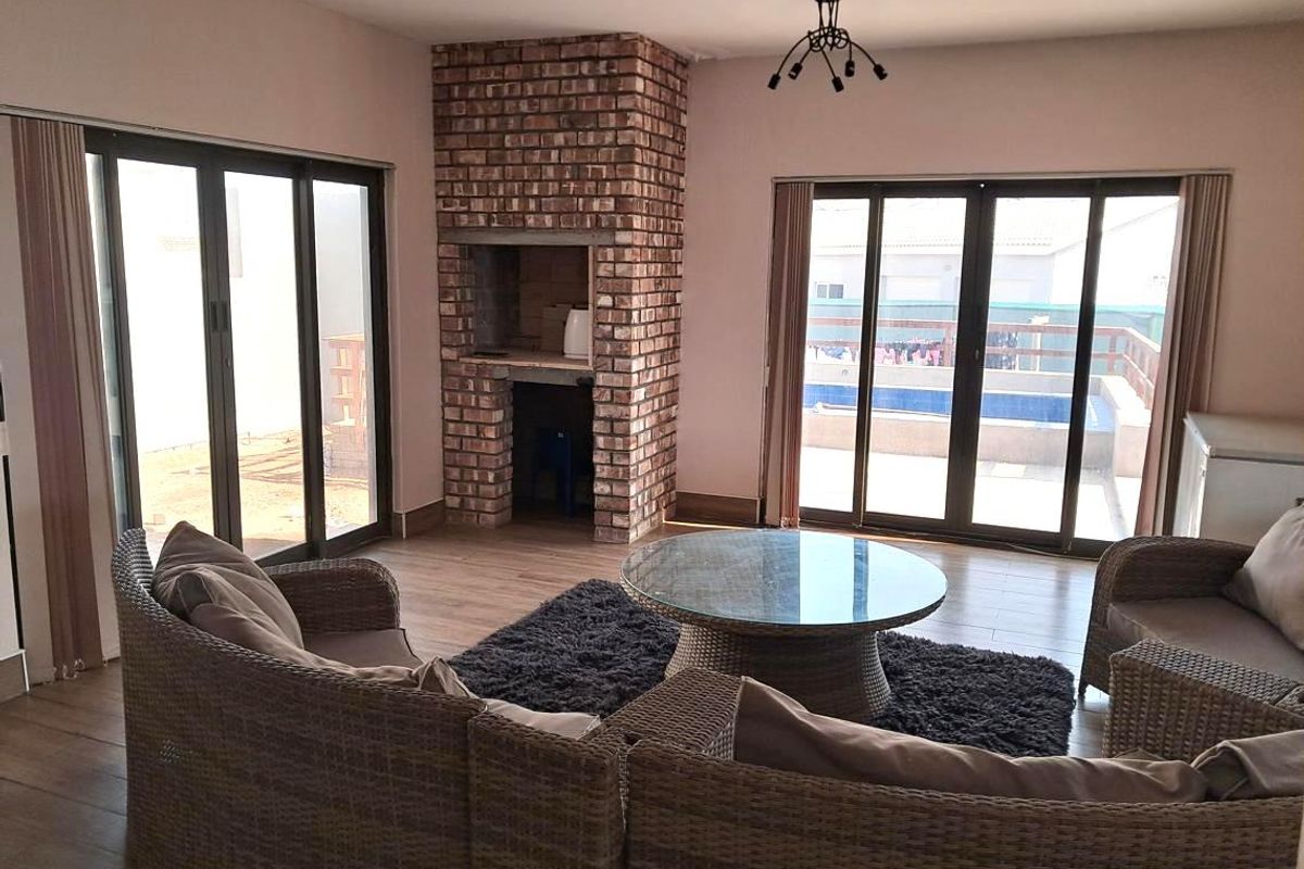 Spacious living area featuring a built-in brick fireplace, laminate flooring, and large sliding glass doors providing access to the outdoor pool area.