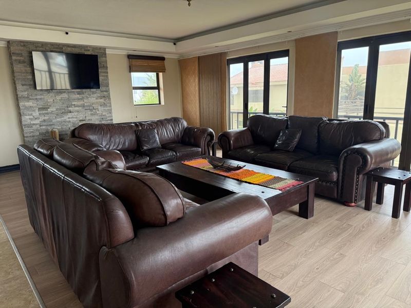 Spacious living room featuring a stone-clad feature wall, modern laminate flooring, and large aluminium sliding doors providing access to the exterior.