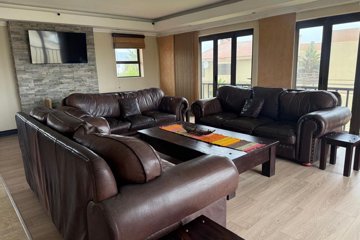 Spacious living room featuring a stone-clad feature wall, modern laminate flooring, and large aluminium sliding doors providing access to the exterior.