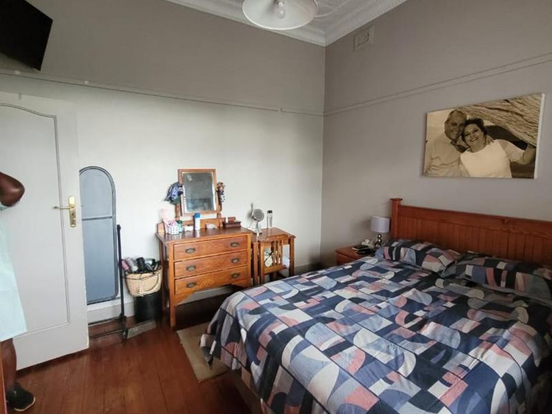 A bedroom featuring original pressed metal ceilings, a decorative ceiling rose, timber flooring, and a classic picture rail.