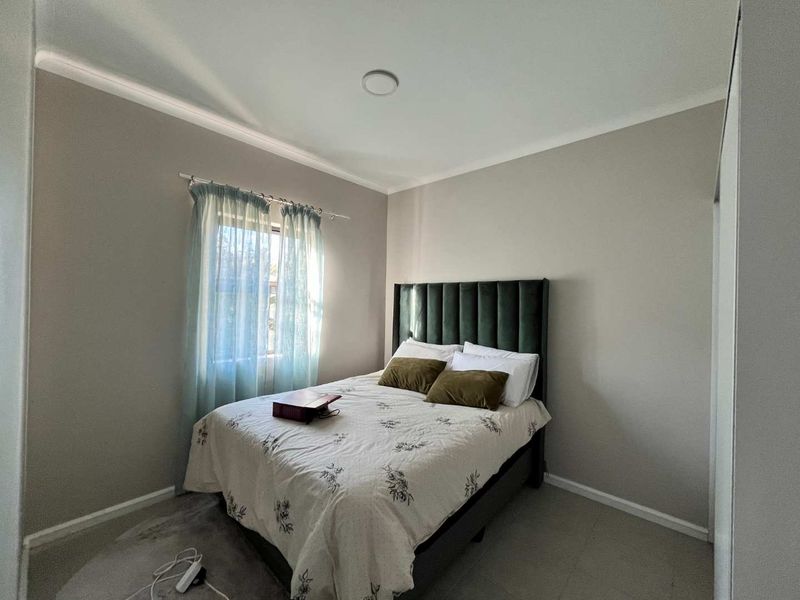 A well-maintained bedroom featuring neutral wall tones, coving, a built-in cupboard, and a recessed ceiling light.