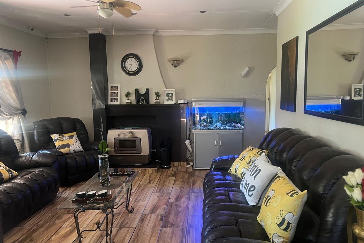 A comfortable living room featuring wood-look tile flooring, a central fireplace, and a ceiling fan, creating a warm and inviting atmosphere.