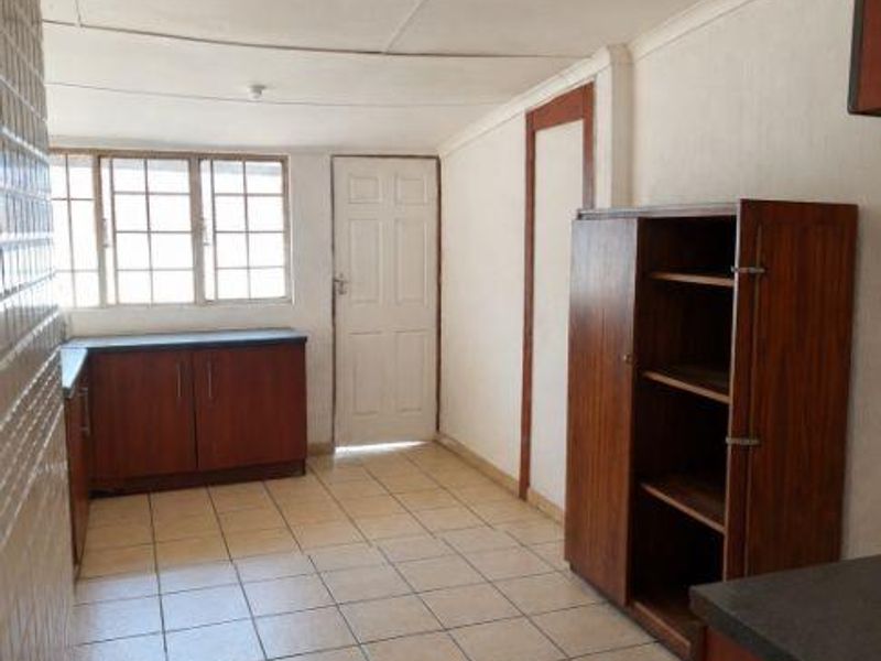 A functional kitchen space featuring built-in cabinetry, tiled flooring, and natural light, offering potential for modernization and cosmetic updates.
