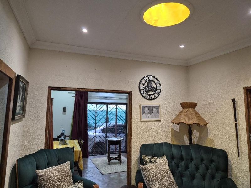 A living room featuring coved cornicing, recessed lighting, and a circular skylight, with a doorway leading to an exterior area with security gates.