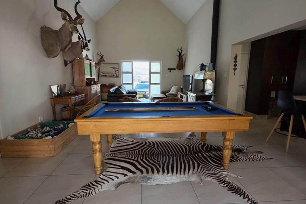 Spacious living area featuring a high vaulted ceiling, tiled flooring, and a prominent freestanding fireplace, offering a versatile open-plan layout.