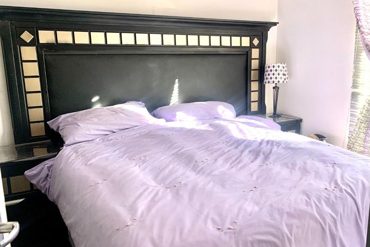 A bedroom featuring a large built-in headboard with integrated side tables and tiled flooring.