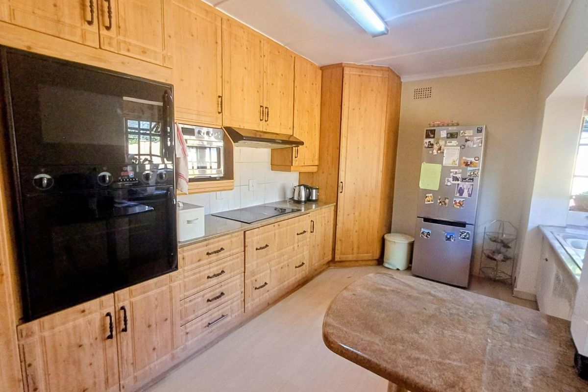 A functional kitchen featuring extensive wooden cabinetry, built-in oven and microwave, electric hob, and laminate countertops with a tiled backsplash.