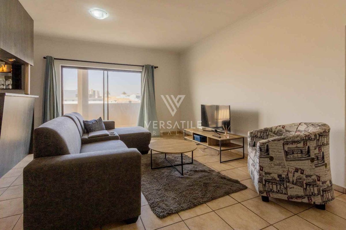 A well-lit living room featuring tiled flooring and a large sliding glass door providing access to the outdoor area.