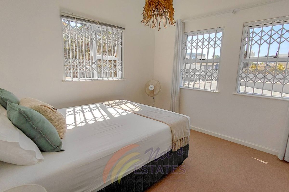 A bright bedroom featuring neutral carpeting, white walls, and security gates on the windows, providing a secure and well-lit living space.