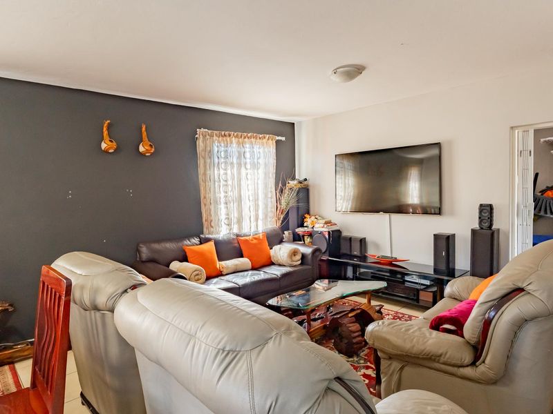 A comfortable living room featuring tiled flooring and a dark accent wall, providing a functional space for relaxation and entertainment.