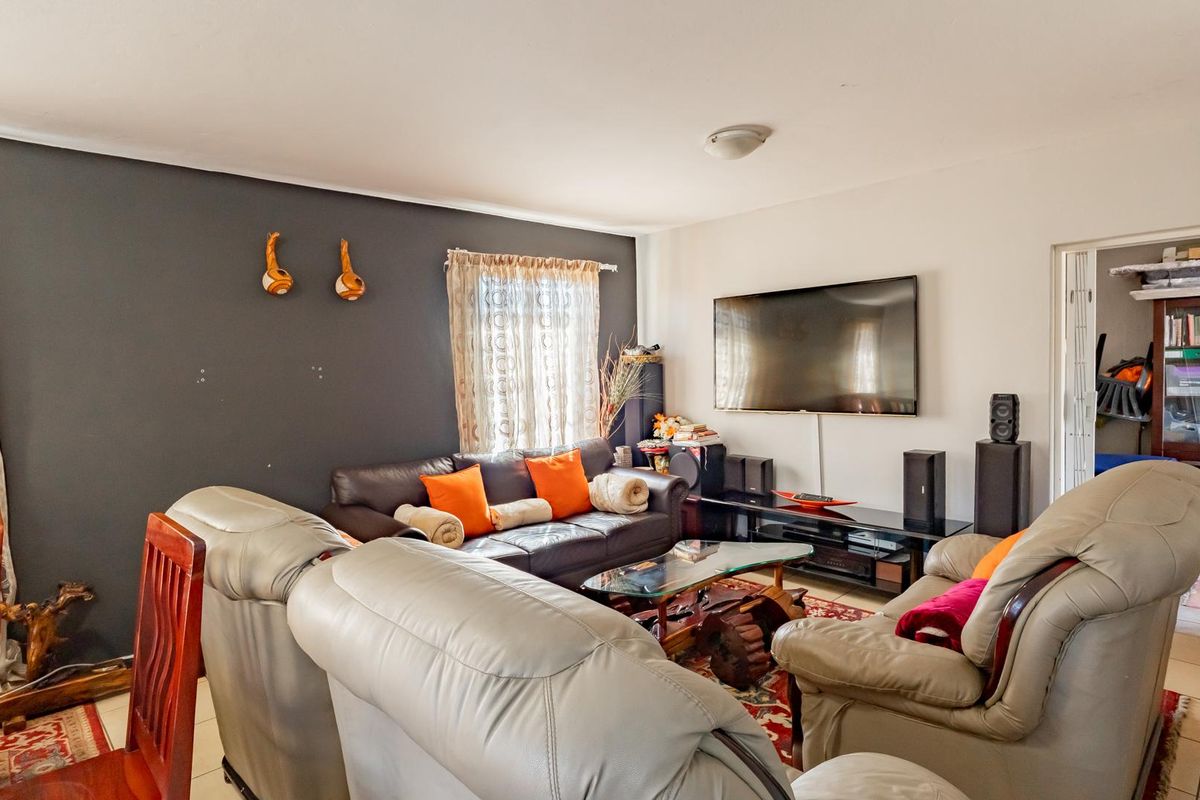 A comfortable living room featuring tiled flooring and a dark accent wall, providing a functional space for relaxation and entertainment.