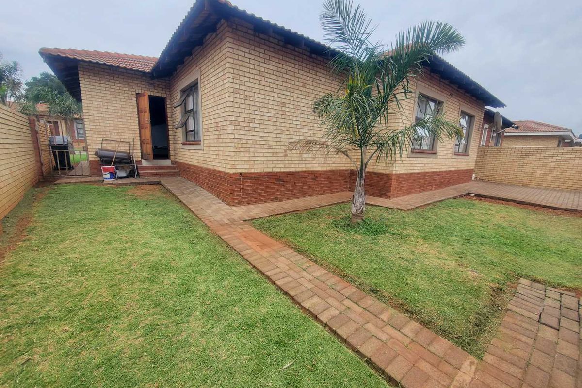A view of the rear exterior of the house, featuring face-brick walls, a tiled roof, paved walkways, and a private garden area.