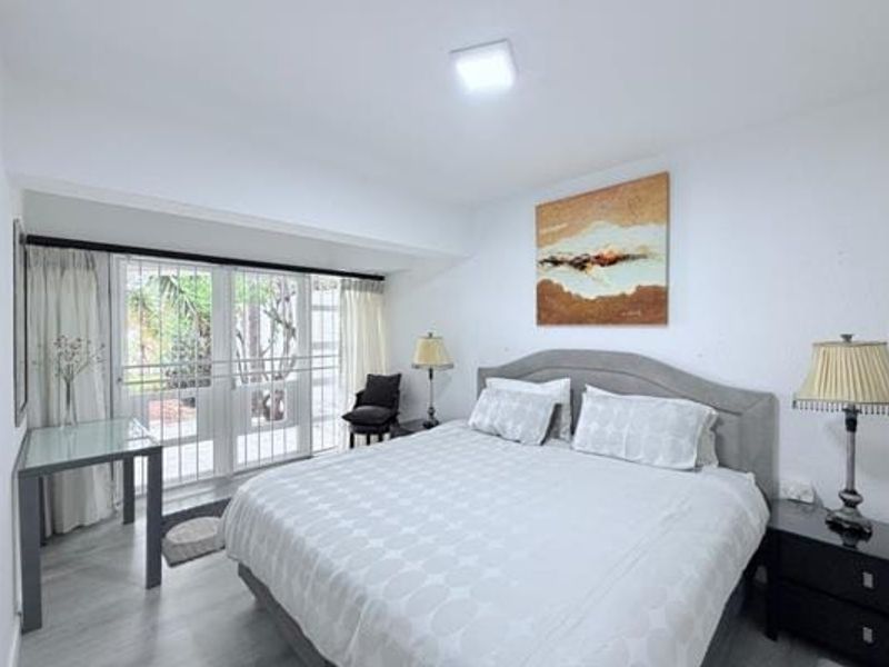 A well-lit bedroom featuring laminate flooring and a sliding glass door with a security gate, providing direct access to the outdoor area.