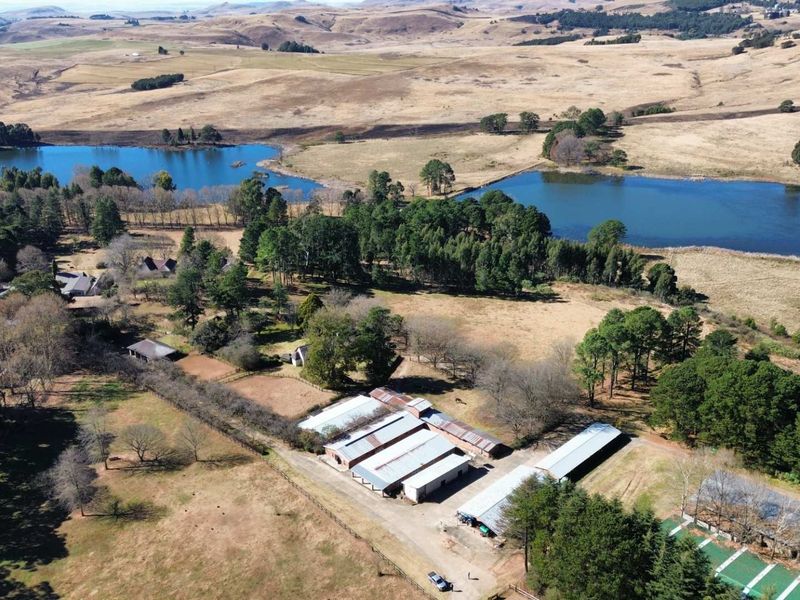Aerial view of a large farm property featuring multiple outbuildings, dams, and expansive surrounding landscape.