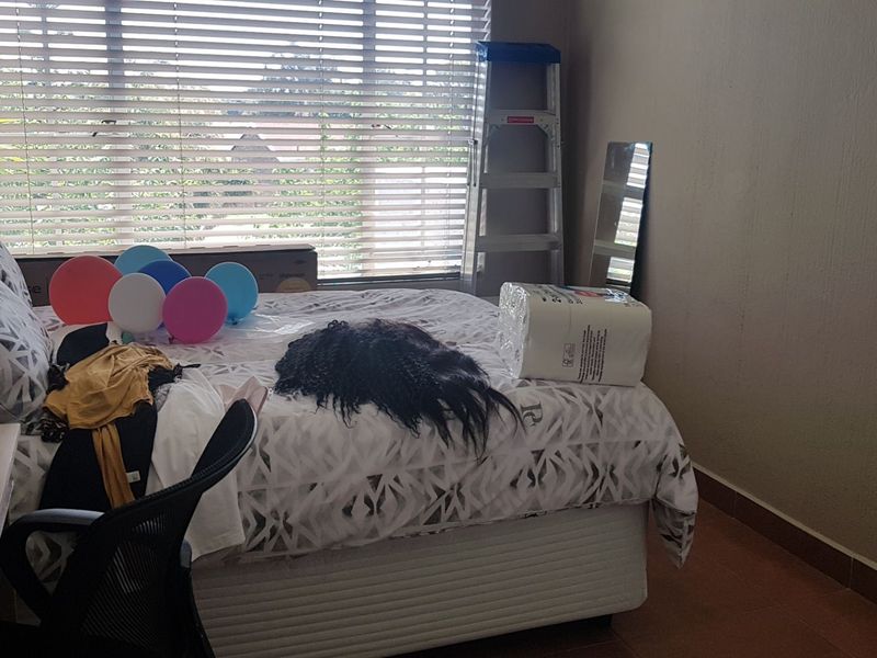 A bedroom featuring tiled flooring and venetian blinds, providing a functional space with natural light.