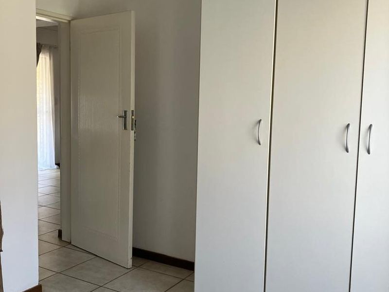A clean, empty bedroom featuring neutral tiled flooring and white built-in cupboards, offering a blank canvas for personalization.