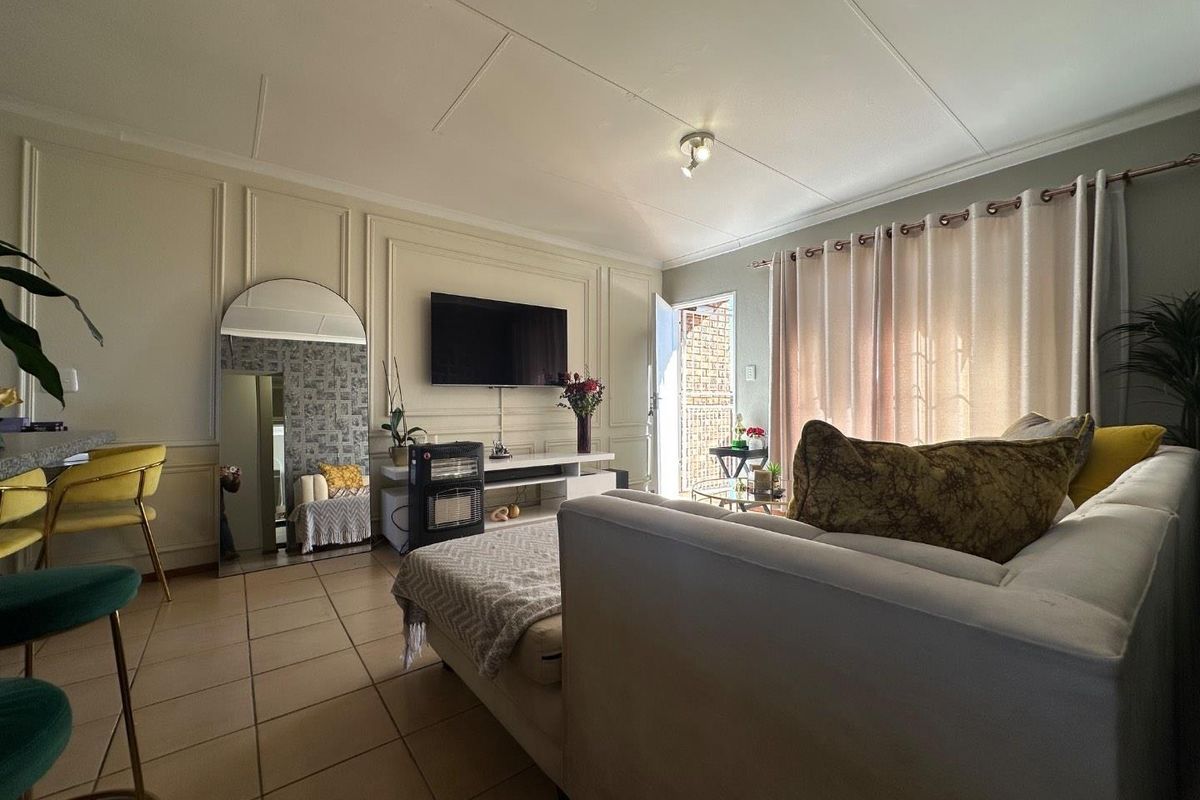 A living room featuring decorative wall paneling, tiled flooring, and access to an outdoor area through a glass door.