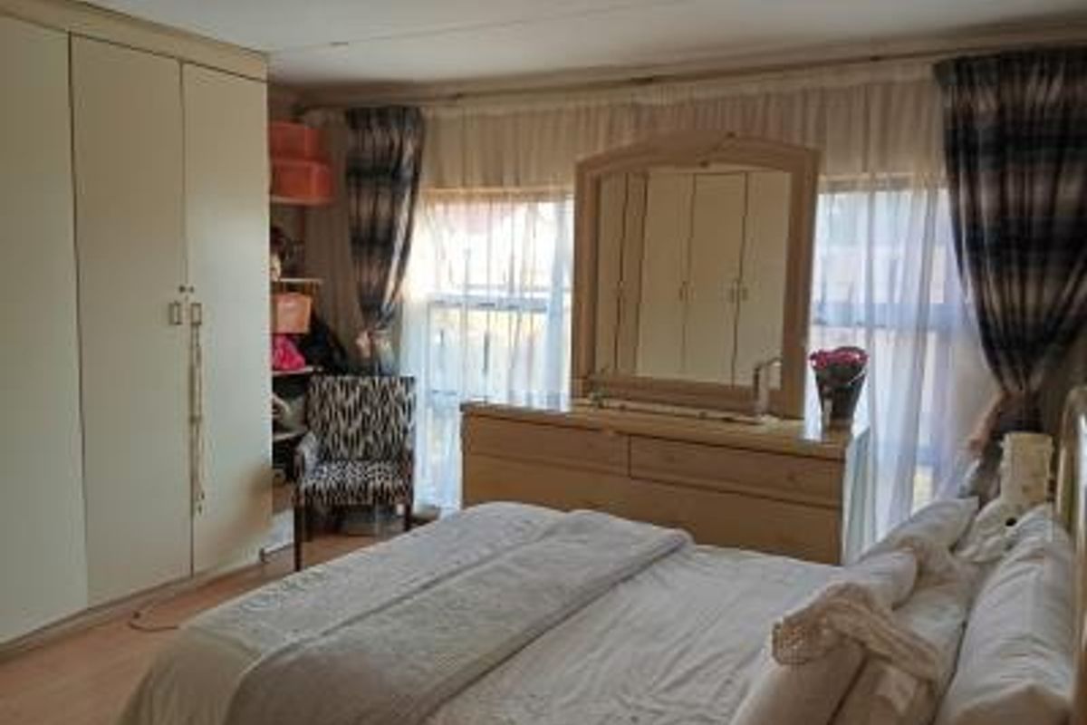 A bedroom featuring built-in cupboards and large windows with natural light.