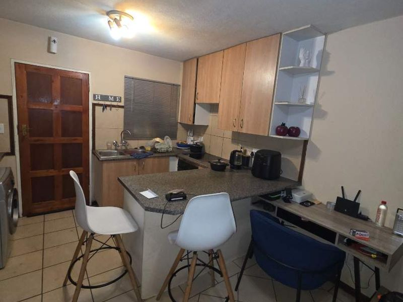 Open plan kitchen area featuring built-in cabinetry, laminate countertops, and tiled flooring, providing a functional layout for daily living.