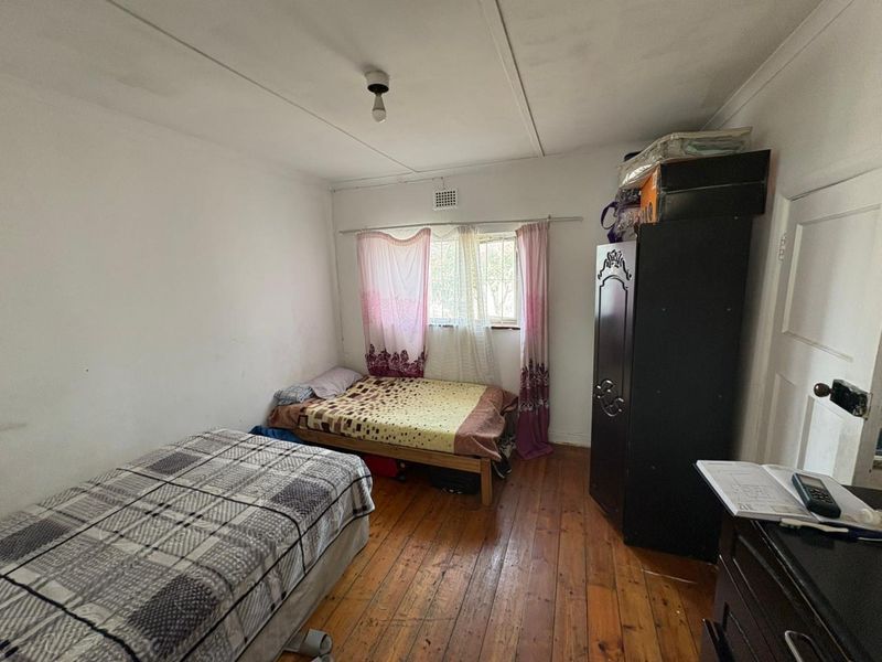 A bedroom featuring original timber flooring and a window with ventilation brick, requiring cosmetic updates to improve the overall finish and appeal.