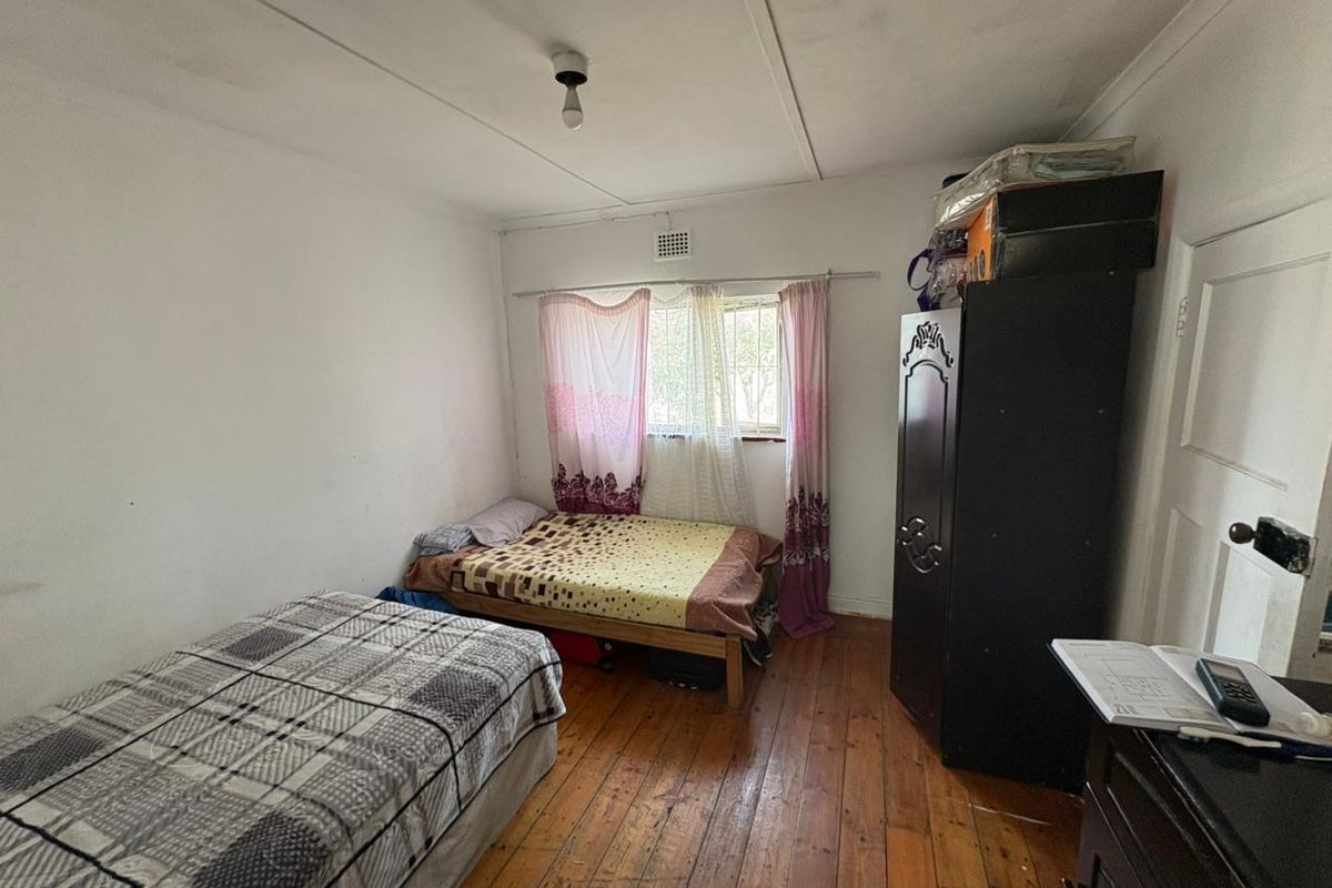 A bedroom featuring original timber flooring and a window with ventilation brick, requiring cosmetic updates to improve the overall finish and appeal.