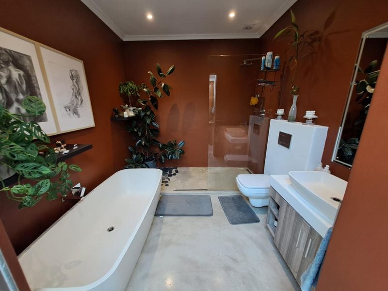 Modern bathroom featuring a freestanding bathtub, a walk-in glass shower, a wall-mounted toilet, and a vanity with a vessel sink.