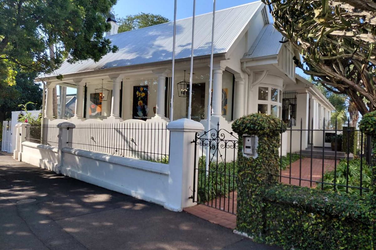 Charming heritage-style commercial property featuring a covered veranda with classic columns, secure wrought iron fencing, and well-maintained exterior finishes.