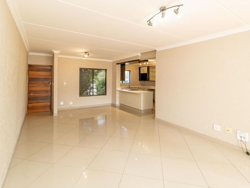 An open-plan living area featuring tiled flooring, a kitchen island with built-in cabinetry, and a wooden entrance door.
