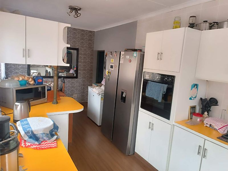 A functional kitchen featuring white cabinetry, yellow laminate countertops, and a built-in oven, offering a practical layout for daily meal preparation.